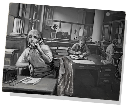 a black and white photo of Karin. she is sitting in an office setting while on the phone. her jacket hangs on the back of her chair and in the background other people are working.